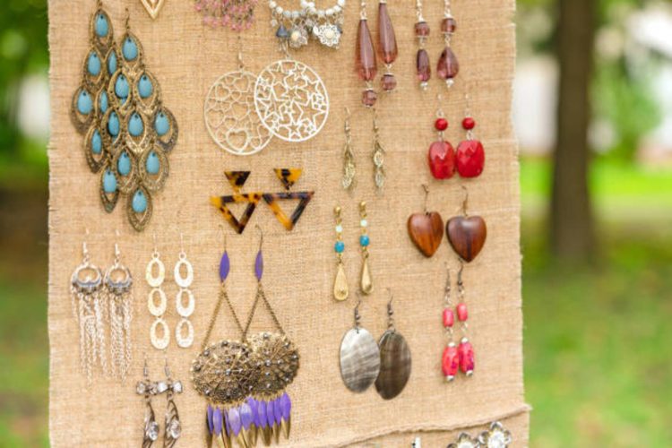 Vintage old-fashioned earrings at flea market stall, yard sale or car boot sale. Retro style jewelry. Vintage goods in boho style for sale. Garage sale concept. Selective focus